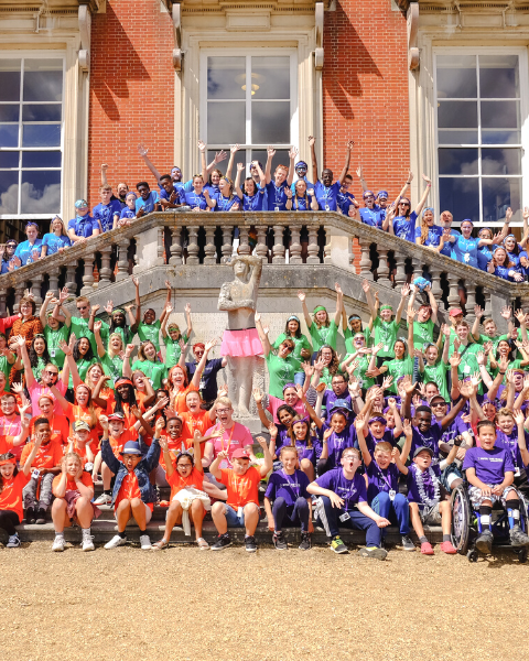 Group of young campers in coloured tops cheering with excitment