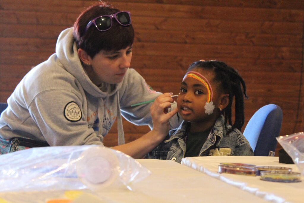Camper and volunteer applying face paint